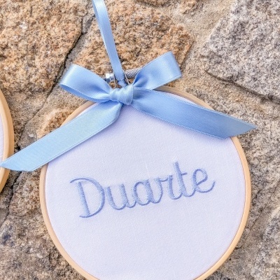 Aro de bordado redondo com nome Duarte bordado e laço azul sobre pedra
