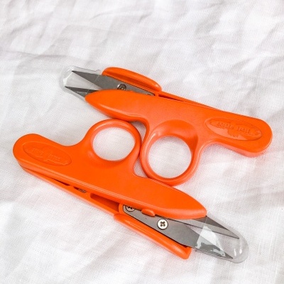 Dois corta unhas laranja sobre tecido branco