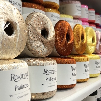 Novelos de fio brilhante Rosários4 Paillettes Classic Collection em cores variadas na prateleira.