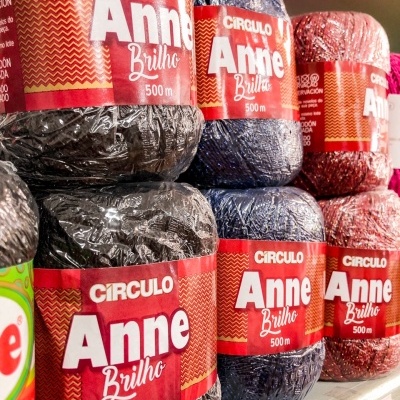 Novelos de lã brilho CÍRCULO Anne em várias cores com etiquetas vermelhas na prateleira