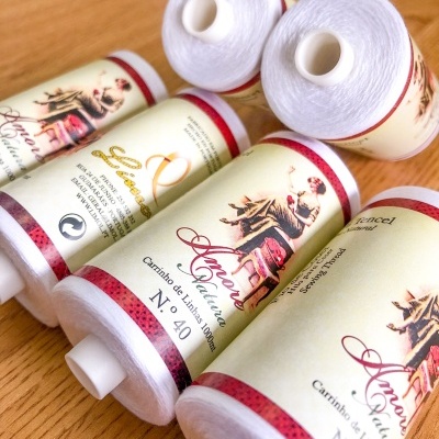 Cinco cones de linha branca com rótulos ilustrados sobre superfície de madeira