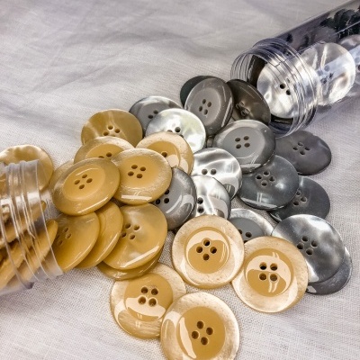Botões redondos bege, pérola e cinza em tecido branco