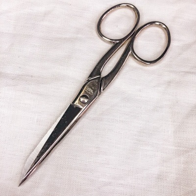 Tesoura metálica prateada sobre tecido branco texturizado