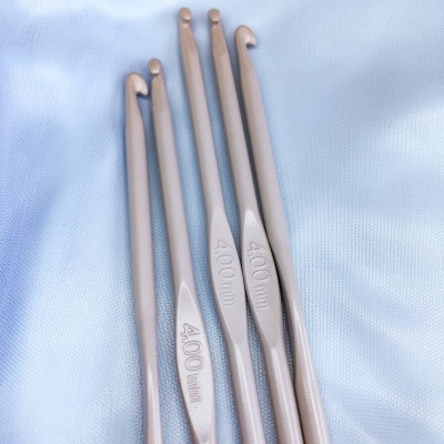 Conjunto de cinco agulhas de croché rosa 4.00 mm sobre tecido azul claro