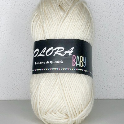 Novelo de lã creme com etiqueta preta, texto OLORA BABY, em fundo branco.