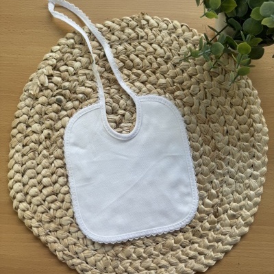 Babete branco em tecido sobre base redonda trançada com planta ao lado