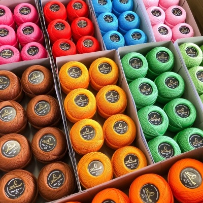 Caixas com rolos de linha de algodão colorida organizados por cor