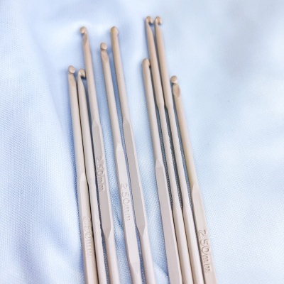 Agulhas de crochet bege claro sobre tecido branco