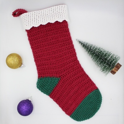 Meia de Natal vermelha, branca e verde em croché, com bolas dourada e roxa e pequena árvore de Natal.