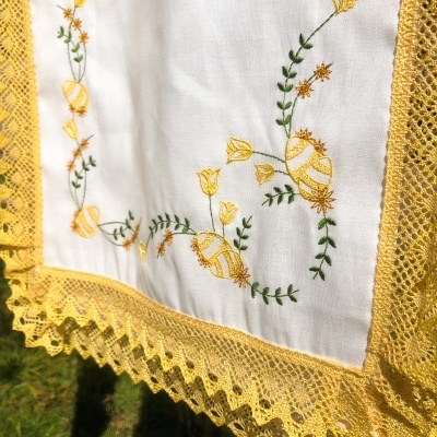 Toalha branca bordada com flores amarelas e renda amarela pendurada