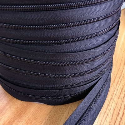 Rolo de fechos éclair pretos com padrão espinha de peixe sobre madeira