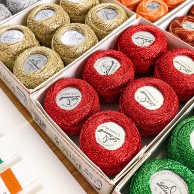 Novelos de linha brilhante de várias cores organizados em caixas com etiquetas 'SPERANZA' e 'OFFICIAL'.