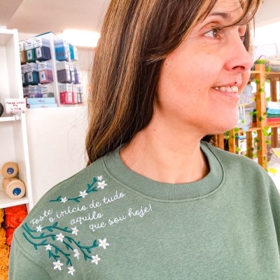 sweatshirt verde com bordado floral e texto perto do ombro esquerdo