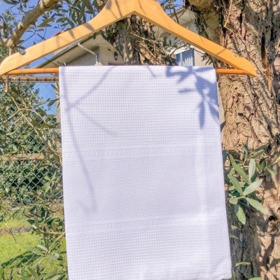 Toalha branca sobre cabide de madeira em exterior com árvores