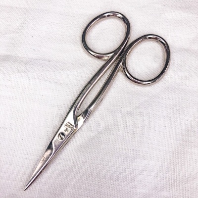 Tesoura metálica pequena sobre tecido branco