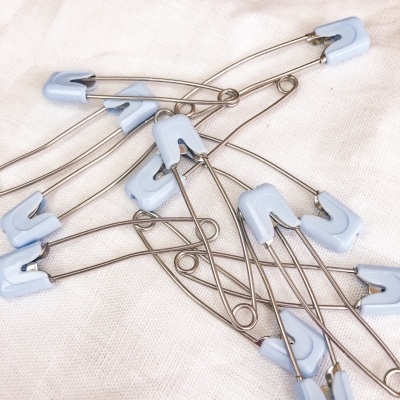 Alfinetes de ama com cabeça azul clara sobre tecido branco