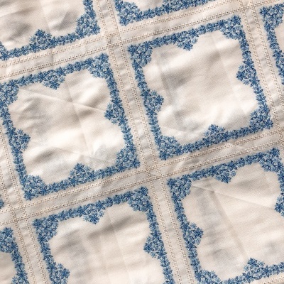 Tecido branco com molduras azuis florais e detalhes castanhos