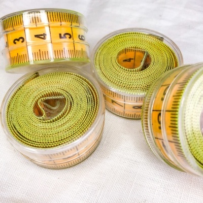 Fitas métricas amarelas em caixas transparentes sobre tecido branco