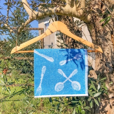 Pano azul com padrões brancos pendurado num cabide de madeira na árvore