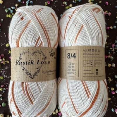 Dois novelos de fio de algodão branco com listras laranja e etiqueta Rustik Love