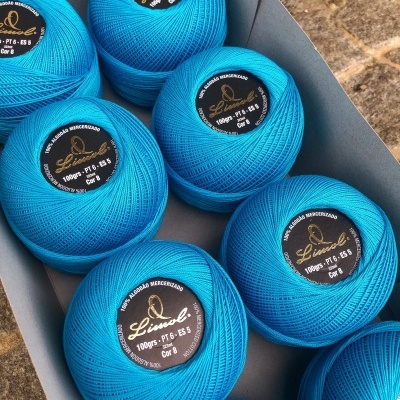 Novelos de linha azul com etiquetas pretas dentro de caixa cinzenta