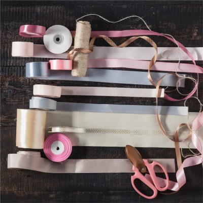 Rolos de fitas coloridas e uma tesoura sobre mesa escura