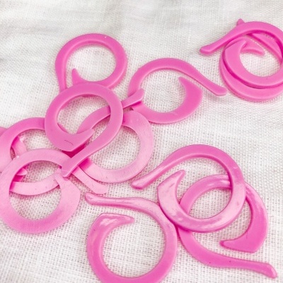 Anéis plásticos cor-de-rosa com gancho sobre tecido branco