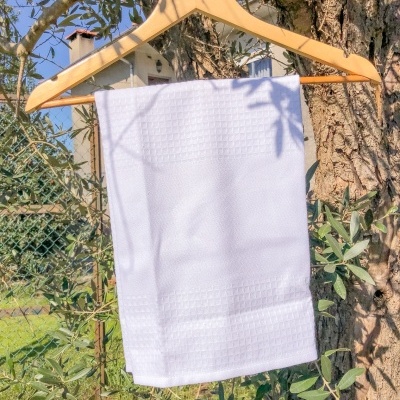 Toalha branca pendurada num cabide de madeira numa árvore ao ar livre