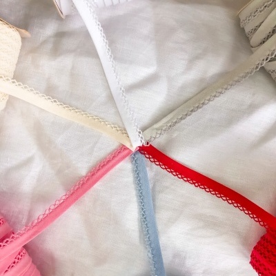 Vários rolos de fitas decorativas coloridas com bordas rendadas sobre tecido branco