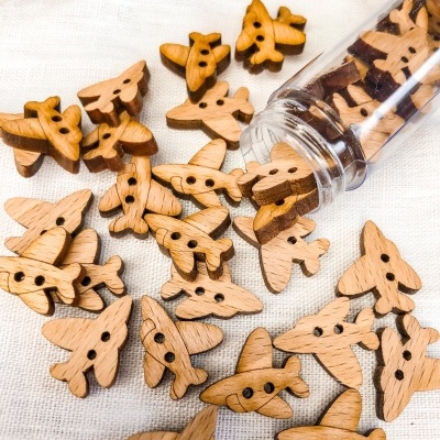 Botões de madeira em forma de avião sobre tecido branco