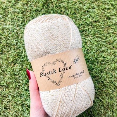 Novelo de fio macramé bege com fios dourados e etiqueta Rustik Love.