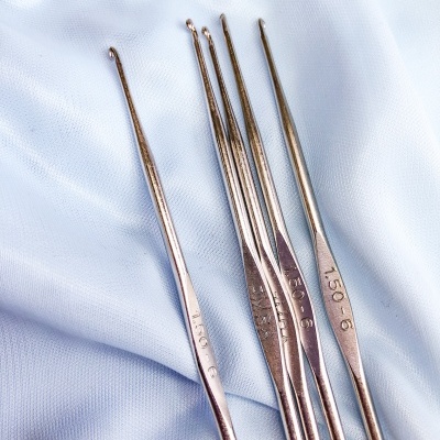 agulhas de crochet metálicas prateadas sobre tecido azul claro