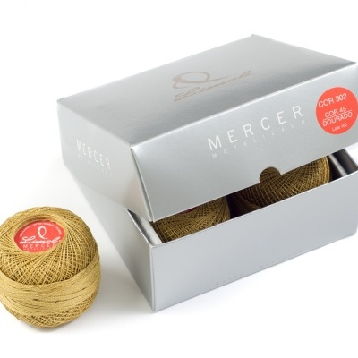 Kit de linha de costura dourada Mercer Metalizado com caixa cinzenta e novelo com etiqueta vermelha.