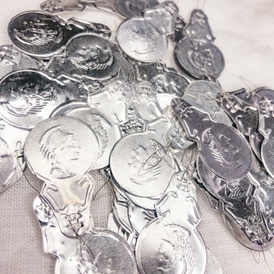 Pendentes metálicos prateados com desenhos em relevo sobre superfície clara