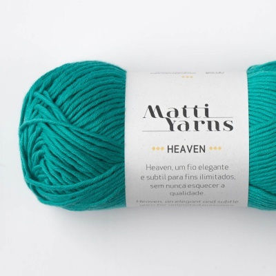 Novelo de fio verde-turquesa com etiqueta branca da marca Matti Yarns e modelo Heaven