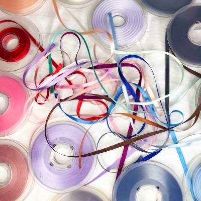 Várias bobinas de fita colorida sobre superfície branca com fitas soltas entrelaçadas