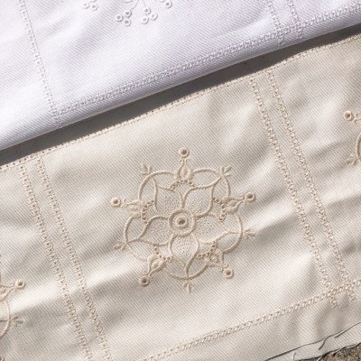 Tecidos branco e bege com bordado floral em relevo