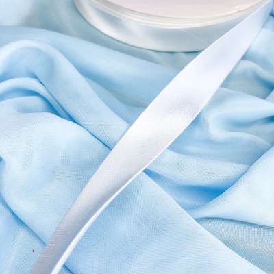 Fita branca satinada sobre tecido azul claro