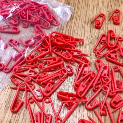 Alfinetes de segurança vermelhos de plástico em superfície de madeira