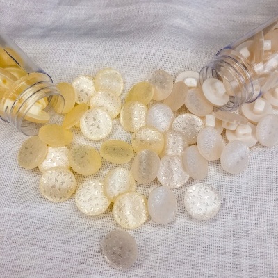 Botões transparentes e amarelos sobre tecido branco com frascos plásticos