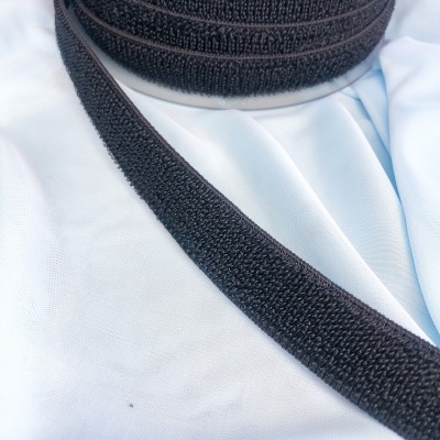 Rolo de fita adesiva preta tipo velcro sobre tecido azul claro