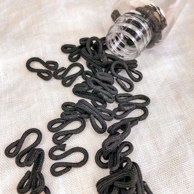 Frascos de plástico com elásticos pretos em forma de oito sobre tecido branco