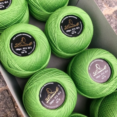 Novelos de linha de algodão mercerizado verde claro numa caixa cinzenta