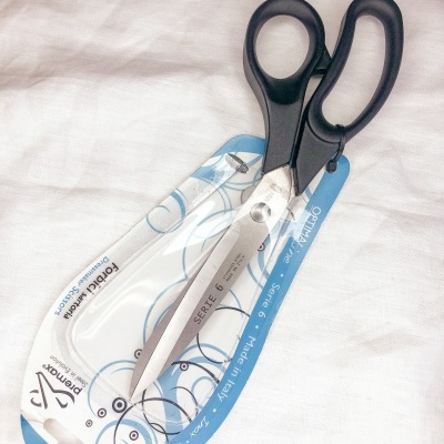 Tesoura de cortar com lâminas em aço inoxidável e cabos pretos em embalagem de cartão branca e azul