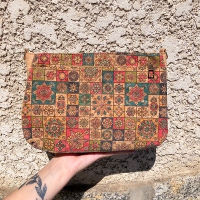 Bolsa de mão com padrão geométrico e floral multicolor e mão tatuda segurando