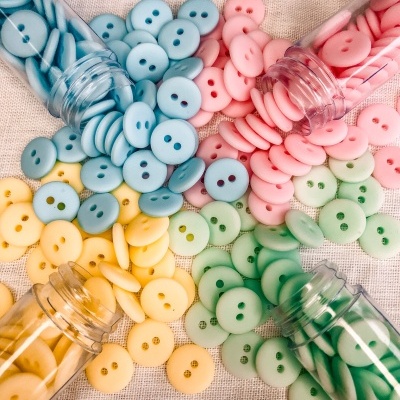 Botões coloridos em frascos sobre tecido claro