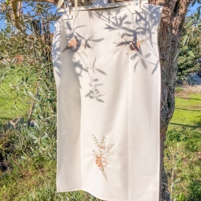 Pano branco bordado pendurado num ramo de árvore em ambiente exterior