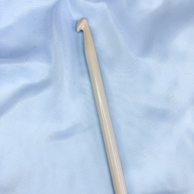 Agulha de crochet bege claro sobre tecido azul claro