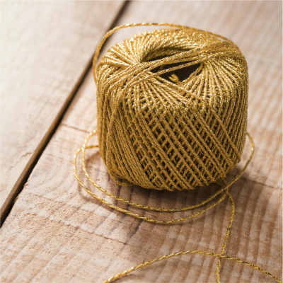 Rolo de cordão dourado brilhante sobre madeira clara