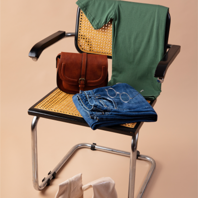 Conjunto de roupa e acessórios sobre cadeira com estrutura metálica e assento de palhinha